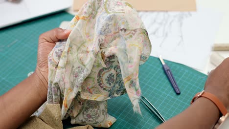 Top-View-Of-Woman-Tailor-Sitting-On-Table-Choosing-Thread-For-Clothing-Pieces-In-Sewing-Workshop