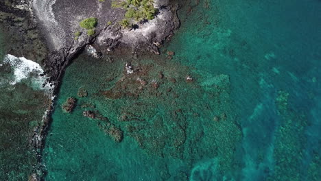 Kristallklares-Wasser-Am-Schwarzen-Sandstrand-Auf-Big-Island-Hawaii,-Das-über-Felsen-Und-Riffe-Schwenkt