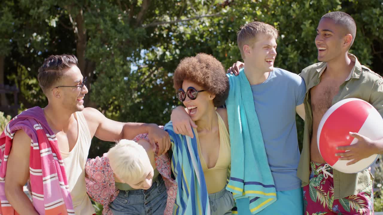 retrato de un grupo feliz y diverso de amigos abrazando y sosteniendo equipos de piscina en verano