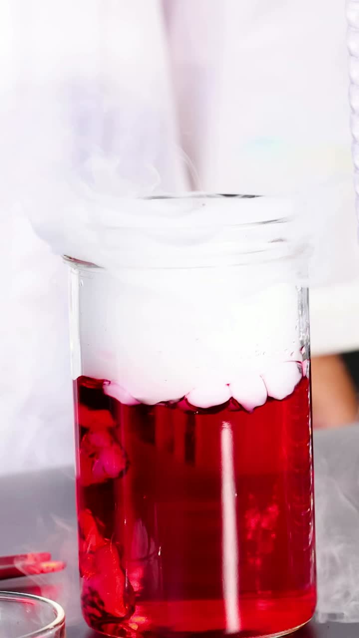 항아리 안의 화학적 반응은 고 있는 연기를 생성합니다. 밝은 빛으로 조명된 실험실 환경에서 포착됩니다.