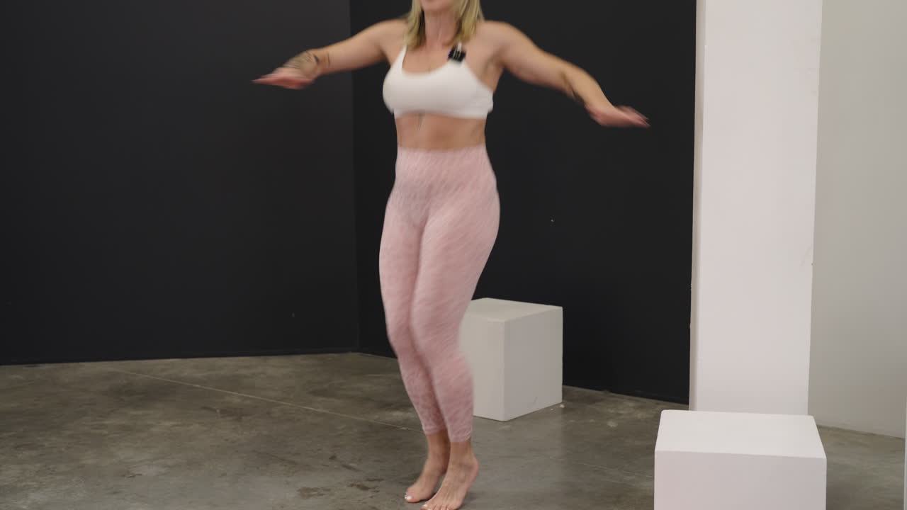 Athletic woman engaging in a dynamic stretching twist and bounce routine during a fitness session indoors