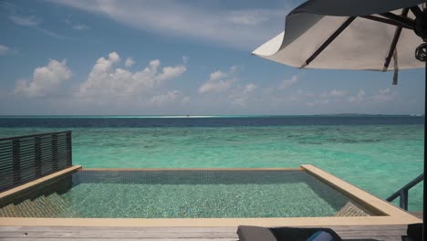 Luxuriöses-Ocean-Villa-Apartment-Im-Malediven-Resort-Mit-Privatem-Pool-Auf-Einer-Holzterrasse-Mit-Sonnenliegen-Und-Sonnenschirm-Und-Wunderschönem-Blick-Auf-Den-Ruhigen-Blauen-Indischen-Ozean