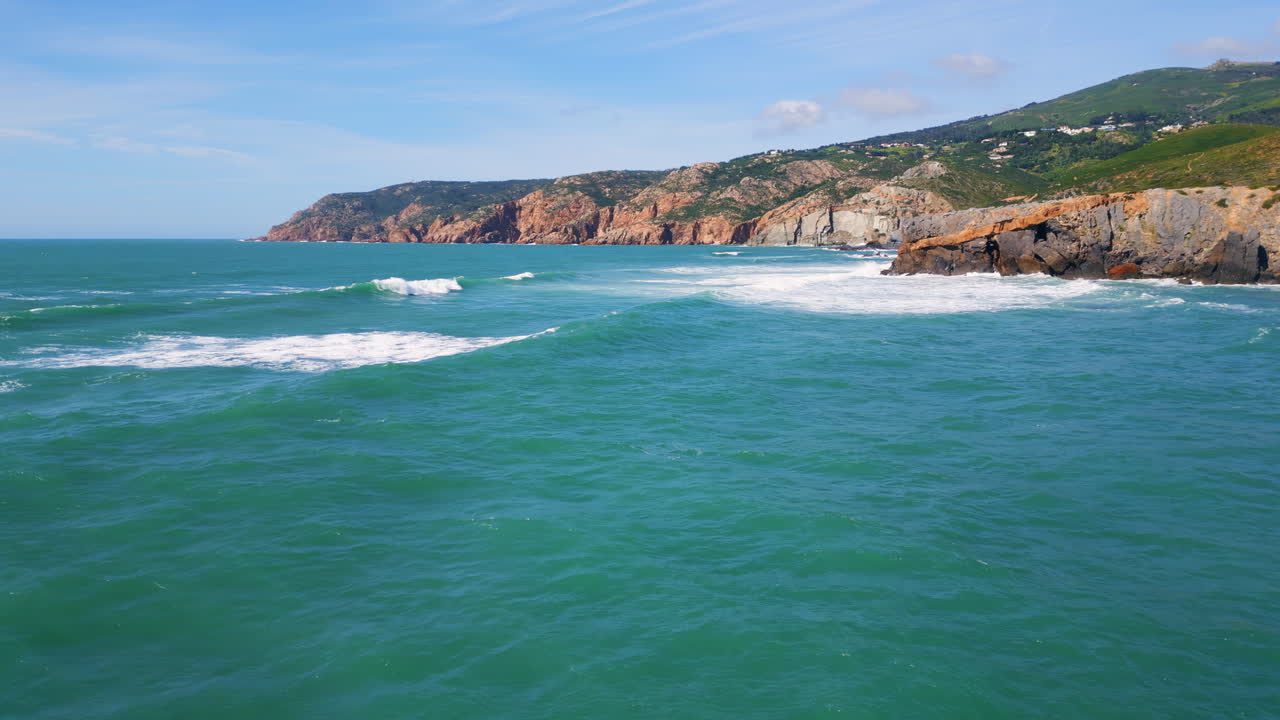 el agua de mar turquesa rodando hacia la orilla rocosa. vista aérea de las olas lavando la costa.