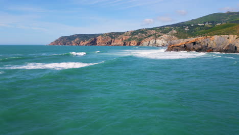turquoise sea water rolling to rocky shore. aerial view waves washing coastline.