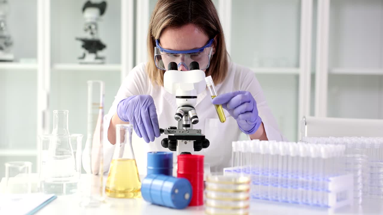 científico que trabaja en un laboratorio con microscopio y tubos de ensayo