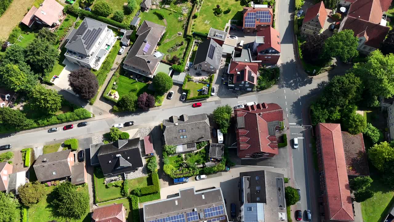 Apartments and single family houses with modern solar panels on roof. Sunny day with green trees and green grass in yard. Aerial top down flyover shot. Small city of America.