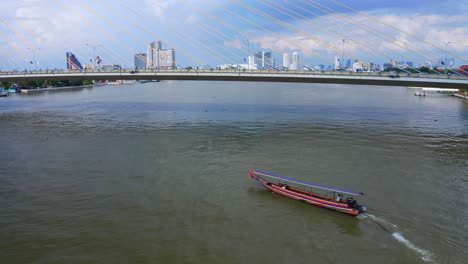 barco de cola larga en el río chao phraya bajo el puente rama viii en bangkok, tailandia