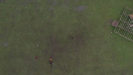 Top-down-shot-of-Indonesian-kids-playing-football-at-a-soccer-field-at-Waikaboebak,-aerial