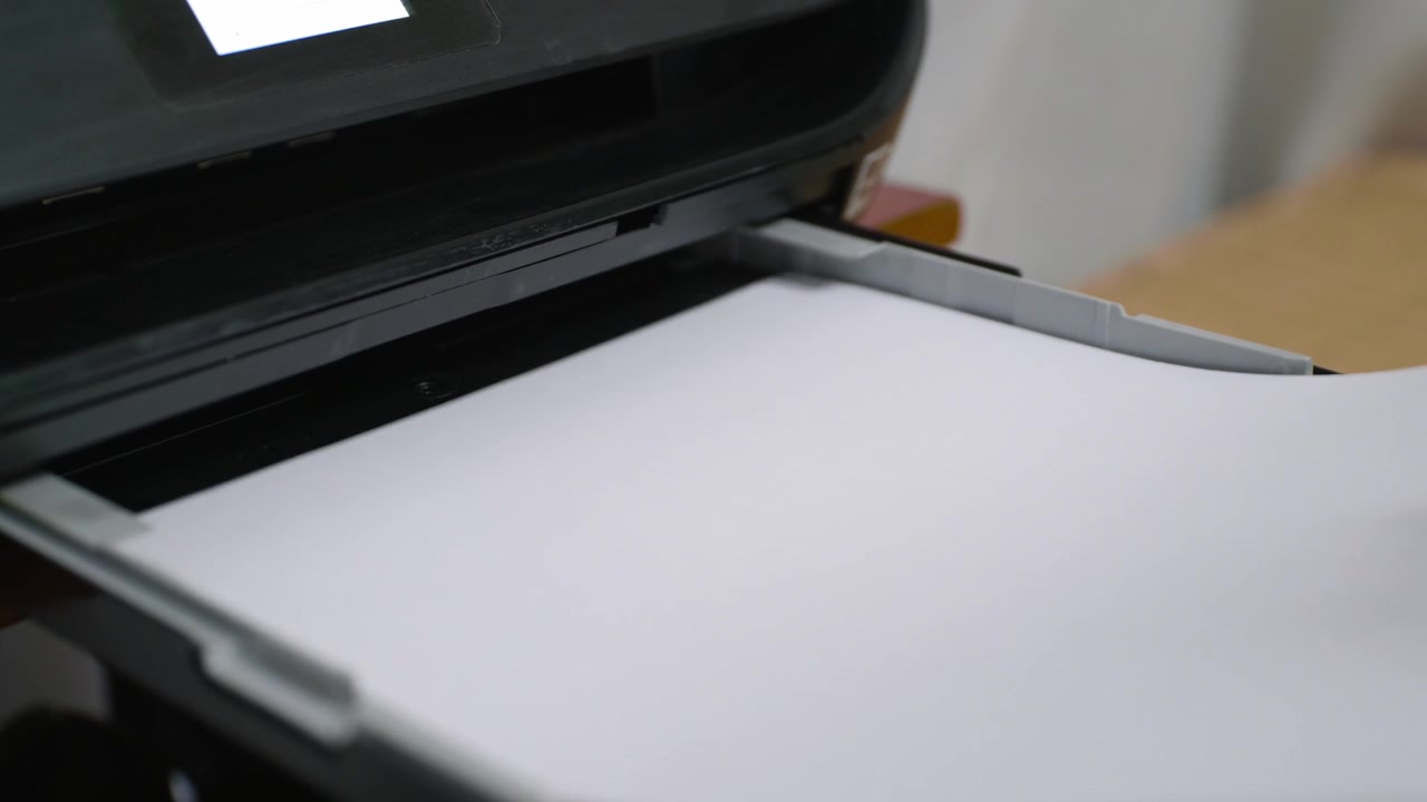 Papel nuevo siendo colocado en una impresora negra de hogar u oficina.