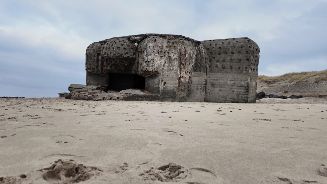 The front part of a WW2 bunker features a large opening for the gun. Beach in Scandinavia.