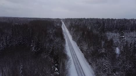 Luftaufnahme-Der-Winterstraßengasse,-Umgeben-Von-Schneebedeckten-Bäumen-An-Bewölkten-Wintertagen,-Kleine-Schneeflocken-Fallen,-Weitwinkel-drohnenschuss-In-Großer-Höhe,-Der-Sich-Vorwärts-Bewegt