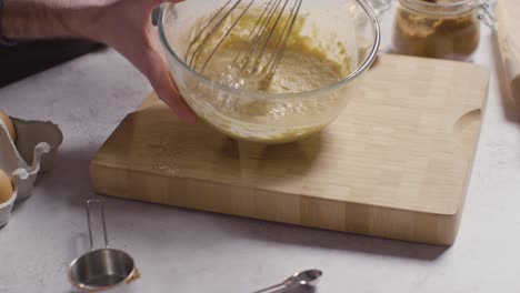 close up of man in kitchen at home whisking ingredients to bowl to bake cake 3