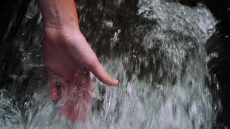 hand gliding trough a small waterfall with clear and fresh and cold water