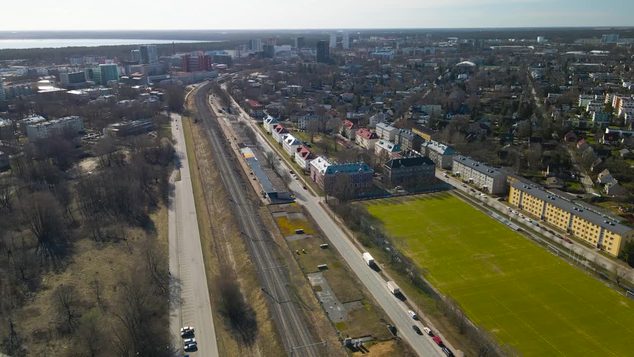 Aerial drone footage of Lilleküla Kristiine neighborhood in Tallinn Estonia during a sunny spring or autumn day. The footage is flying towards the ground or decending showing traintracks or railroad.