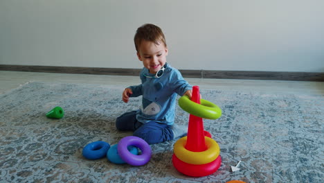 calm caucasian toddler assembling toy pyramid. adorable baby boy playing games at home.