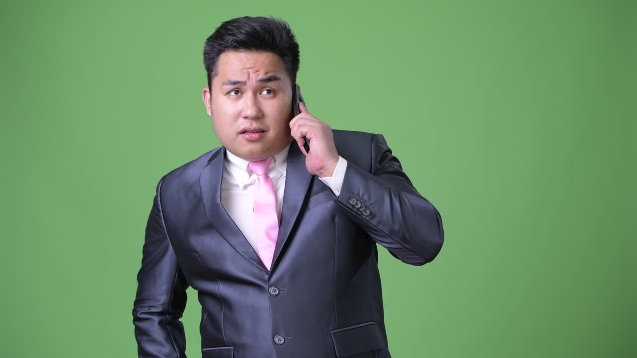 초록색 배경에 젊은 잘생긴 과체중 아시아 사업가