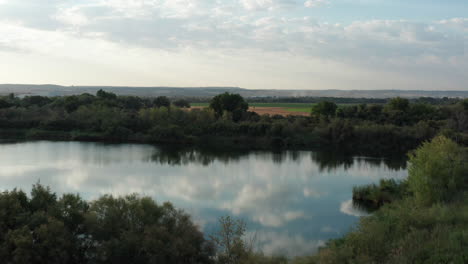 tiro de dron del lago con nubes reflejadas en el agua y el bosque junto al lago