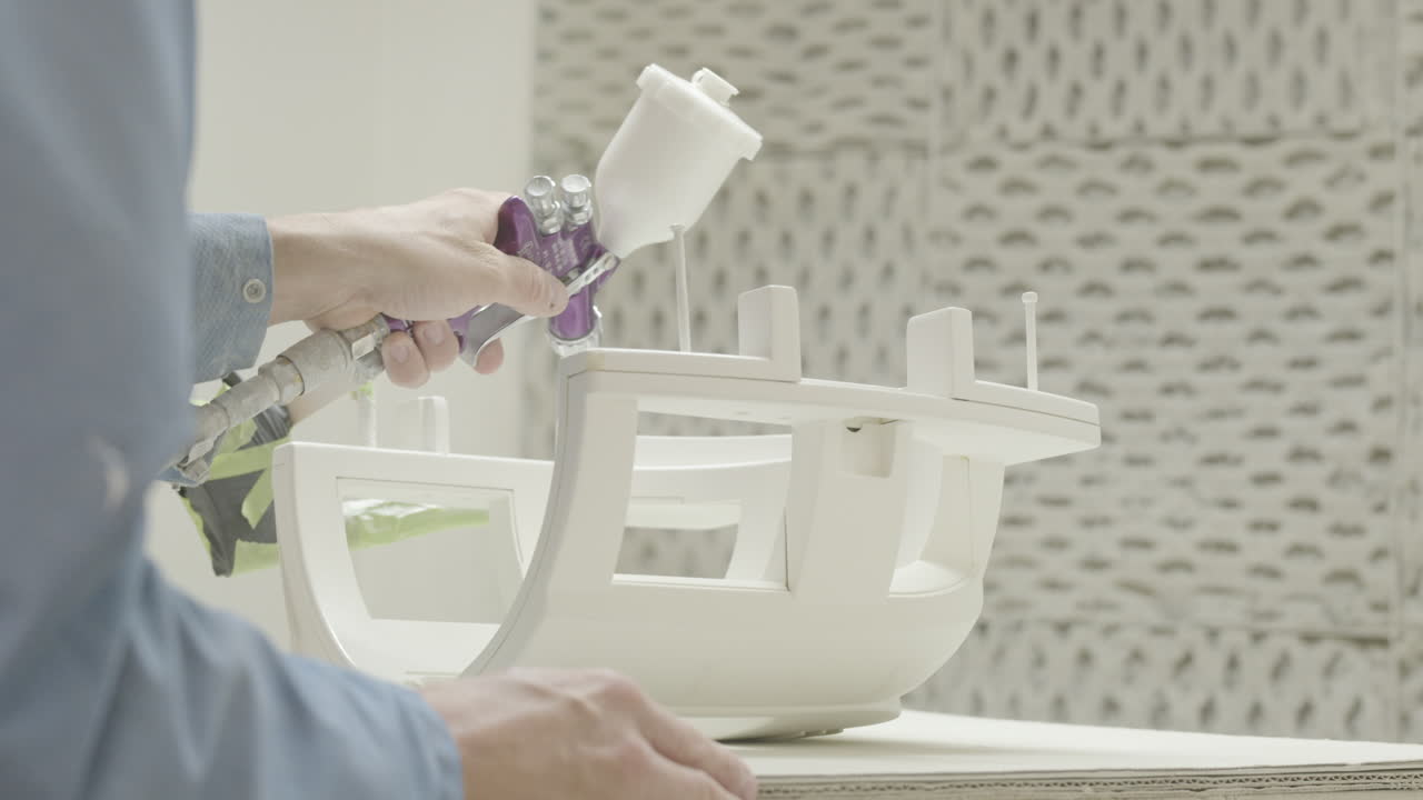 el trabajador usa un aerógrafo para pintar componentes de dispositivos médicos en una cabina de pintura a cámara lenta