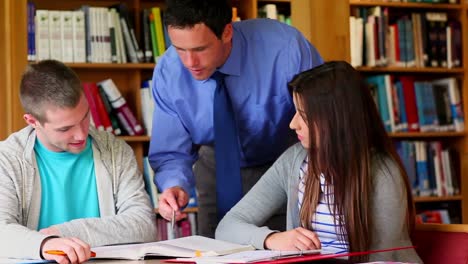 profesor sonriente ayudando a sus estudiantes en la biblioteca
