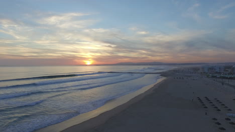 wide horizon drone shot at costa de caparica with some people in the frame on the sea wall