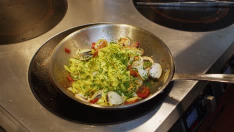 Spaghetti-o-tagliatelle-with-seafood-preparation-in-professional-restaurant-kitchen,-chef-add-green-Persley-before-plate