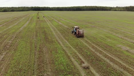 a tractor with a trailed baler, producing baling of straw on a harvested agricultural field