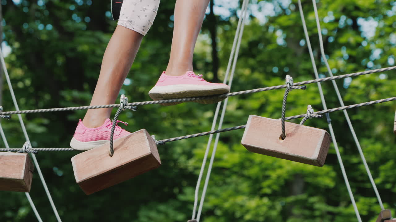 나무 사이에 뻗은 케이블을 따라 걷는 아프리카계 미국인 어린이의 발