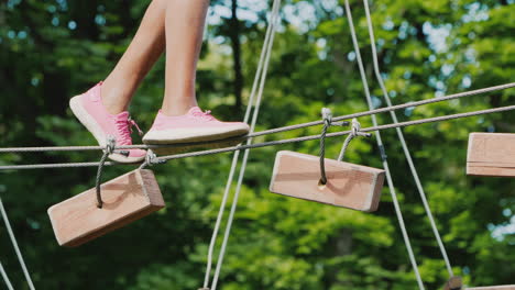 feet of an african american child walking along a cable stretched between trees