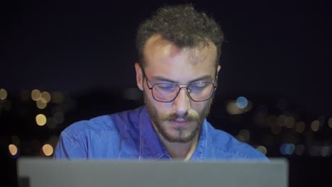 persona que trabaja en una computadora portátil al aire libre por la noche.