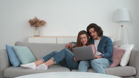 couple relaxing and watching laptop on couch
