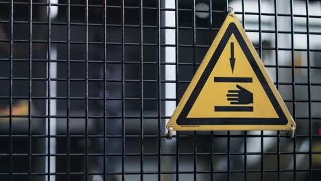 Factory-machine-danger-sign-with-hand-icon-on-grid-conveyor-mechanism-background