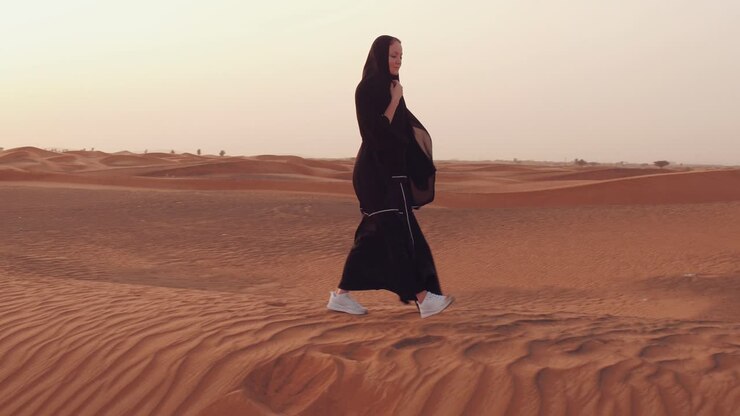 Femme en abaya marchant dans le désert