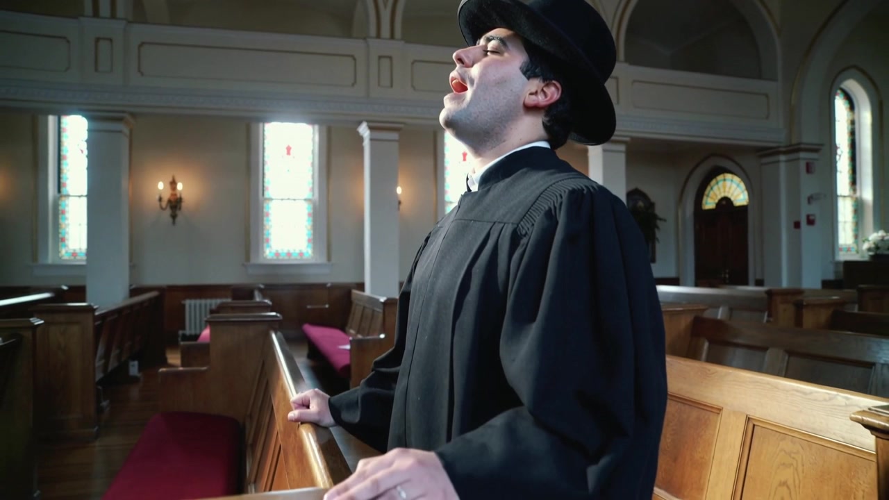 Tief atmend, Geistlicher in schwarzer Robe und Hut singt am Kirchenknieschemel mit Kirchenbänken, Textfreiraum.