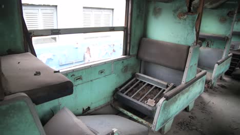 broken seat inside an abandoned train pan to an empty hallway