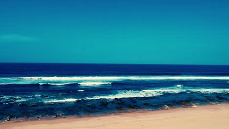 aerial footage filmed with a drone overlooking the beach and sea of crashing waves with a deep blue ocean on the bluff in africa southern hemisphere