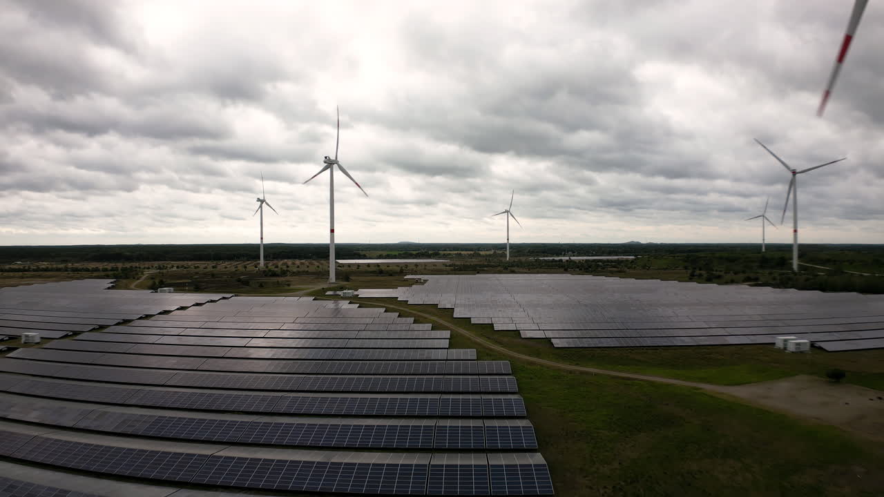 Glowing sky above solar and wind farms, aerial drone view