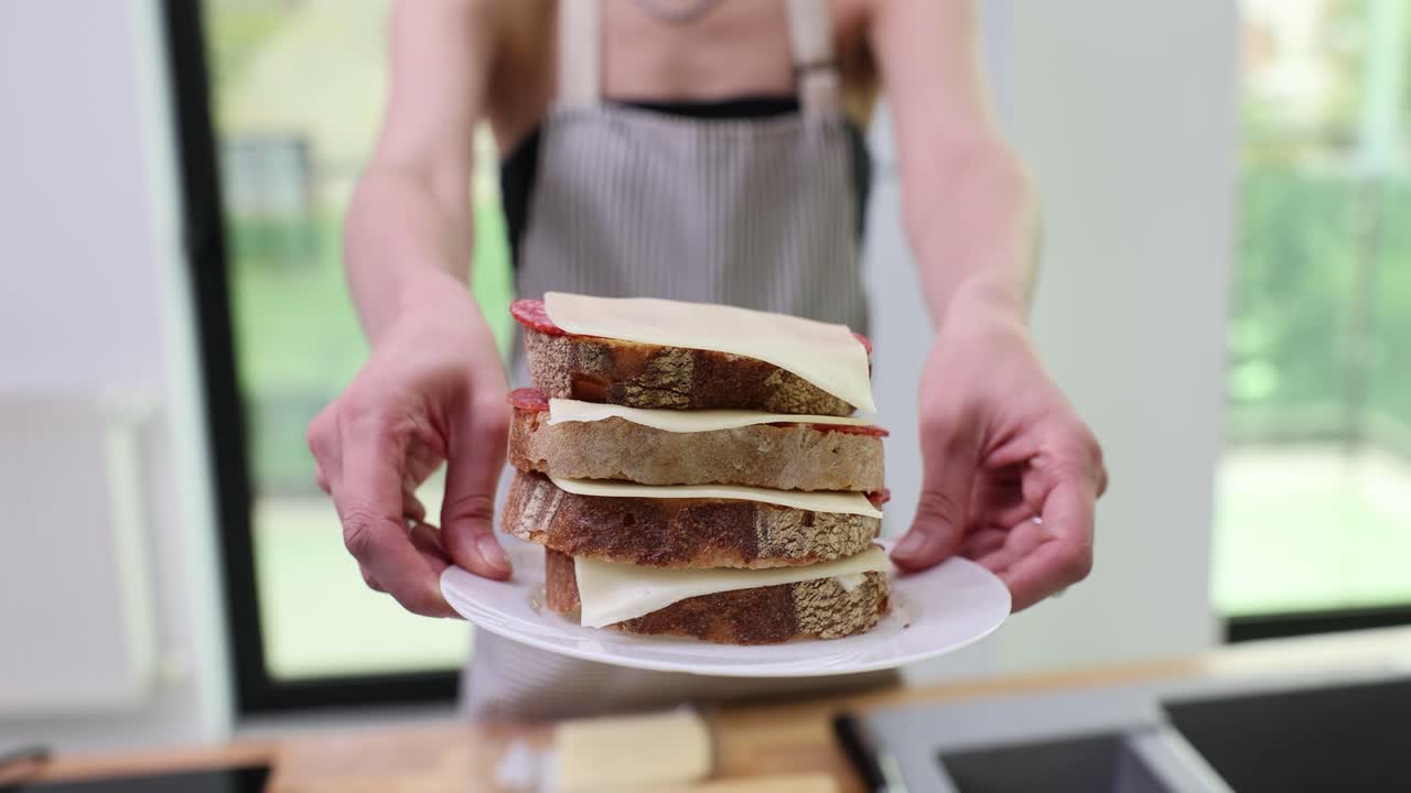Person holding a homemade stacked sandwich on a plate