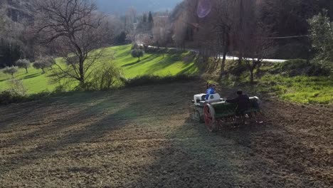 farmer on tractor with seeder sowing the land at sunset, aerial shot