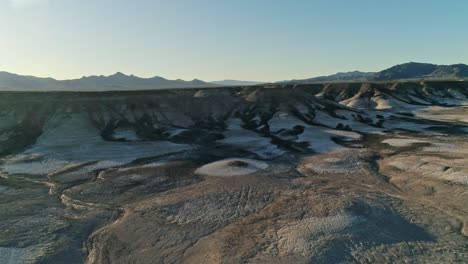 vista aérea lenta y panorámica que se mueve hacia terraplenes secos y áridos de lutita en un desierto