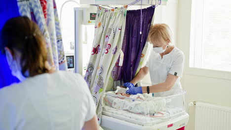 nurse caring for newborn in hospital nursery