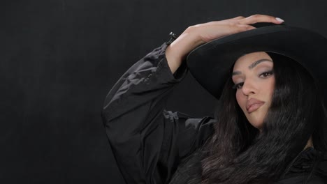 A Beautiful Brunette in a Black Outfit and a Black Hat Poses for the Camera a Beautiful Brunette in a Black Outfit and a Black Hat Poses for the Camera High Quality Footage