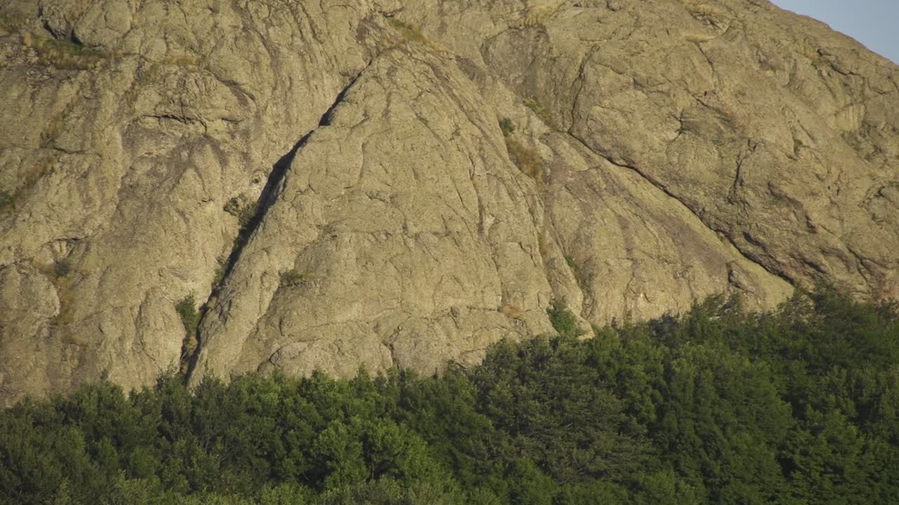 Rocky hill surrounded by trees as the sun sets. Views of the natural landscape. Kutelka Reserve in Sinite Kamani Nature Park. Stara planina above Sliven town. Balkan Mountains
