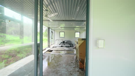 dolly to door entrance into open space half constructed demountable container home with wood supplies and bare corrugated metal roof