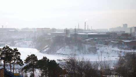 snowy industrial cityscape with river and fog