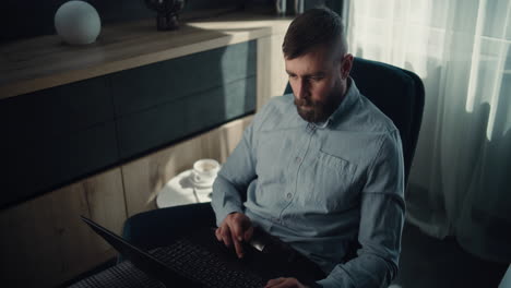 financial expert working on laptop, monitoring real-time stocks and exchange market charts, making investments. successful businessman works in comfortable office of investment bank. dolly shot.