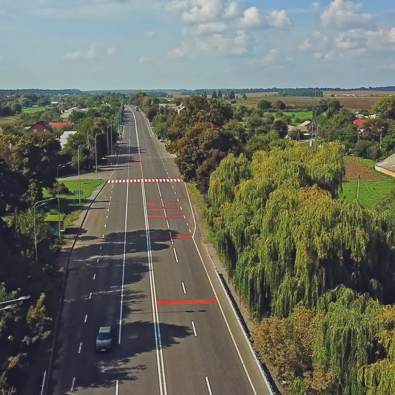 Aerial view through a quiet residential neighborhood along the main street of this small rural town on a clear day. Flying over a newly paved and empty main street in a rural town