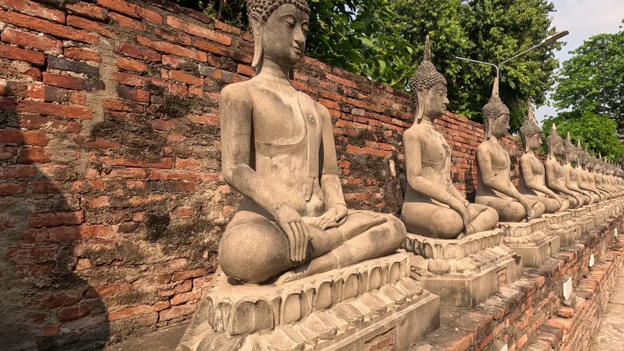 una secuencia de estatuas de buda contra una pared de ladrillo
