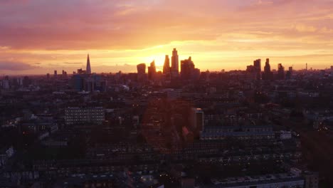 long dolly forward aerial drone shot of beautiful sunset behind city of london skyscrapers