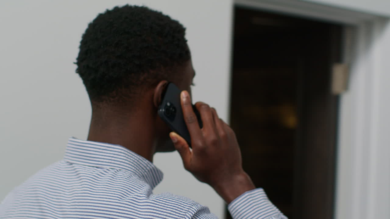 Close Up Of Smiling Young Businessman Walking Along Corridor In Office Talking On Mobile Phone 3