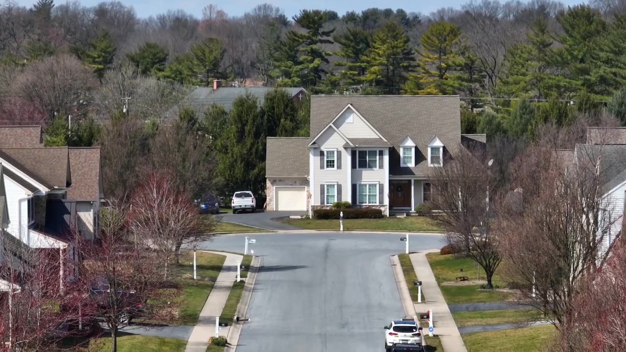 Large family home in suburbs. Rising aerial reveal of church behind house.